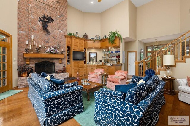 27603 Palo Verde Rd, San Benito, TX 78586 - living area with a towering ceiling, stairway, hardwood / wood-style flooring, a brick fireplace, and baseboards