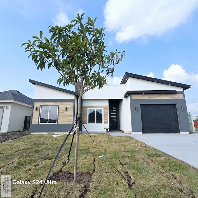 view of front of house with a garage, a front lawn, stucco siding, and concrete driveway