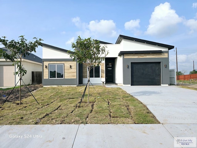 contemporary home with driveway, a front lawn, stucco siding, and an attached garage