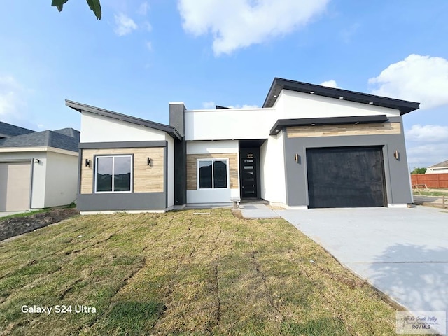 contemporary home featuring stucco siding, concrete driveway, a front yard, and a garage