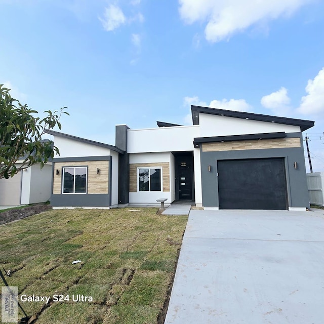 modern home with stucco siding, a front lawn, concrete driveway, and an attached garage