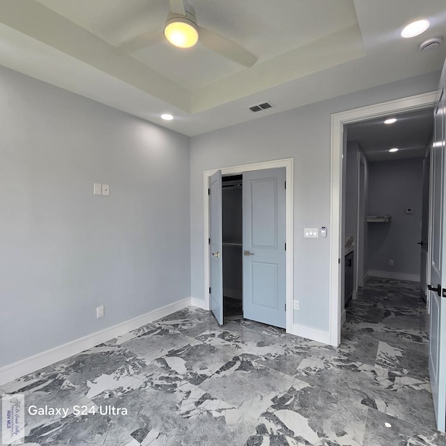 unfurnished bedroom featuring recessed lighting, ceiling fan, a tray ceiling, visible vents, and baseboards