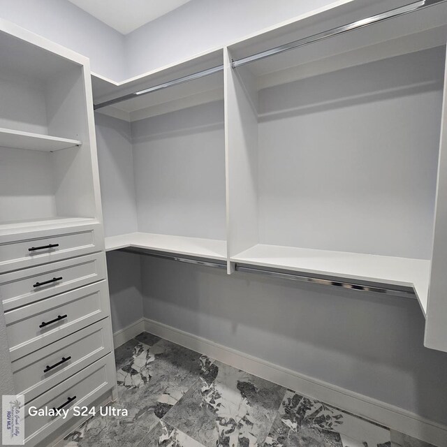 walk in closet featuring marble finish floor