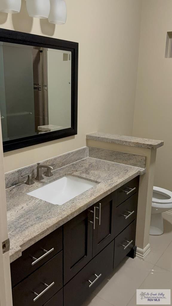 bathroom with baseboards, vanity, toilet, and tile patterned floors