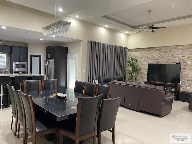 dining area featuring a tray ceiling, a high ceiling, a ceiling fan, and recessed lighting