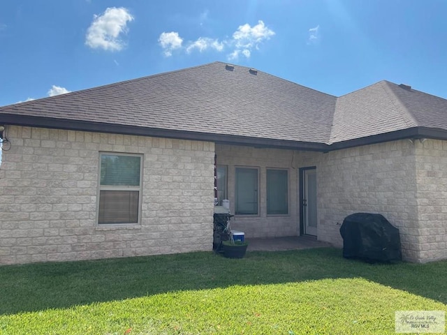 back of property with a shingled roof and a yard