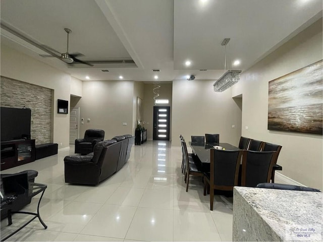 living area with ceiling fan, baseboards, a raised ceiling, and recessed lighting