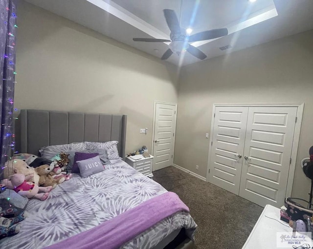 bedroom with visible vents, a closet, dark carpet, and a ceiling fan