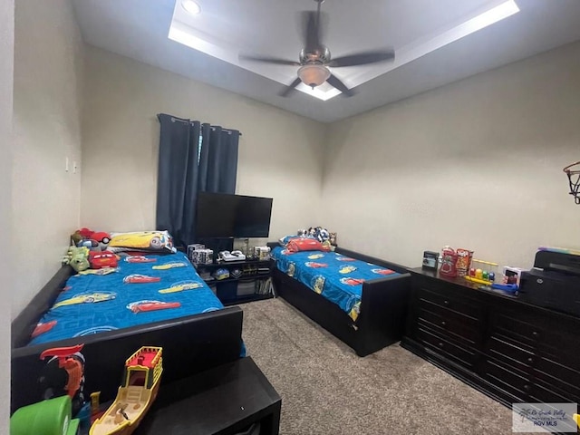 bedroom featuring ceiling fan, a tray ceiling, and carpet