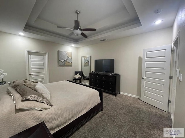 bedroom featuring a ceiling fan, a tray ceiling, baseboards, and carpet