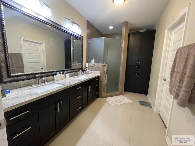 full bathroom with double vanity, a stall shower, a sink, and tile patterned floors