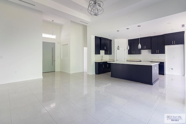 kitchen featuring pendant lighting, a kitchen island, light tile patterned flooring, and a towering ceiling