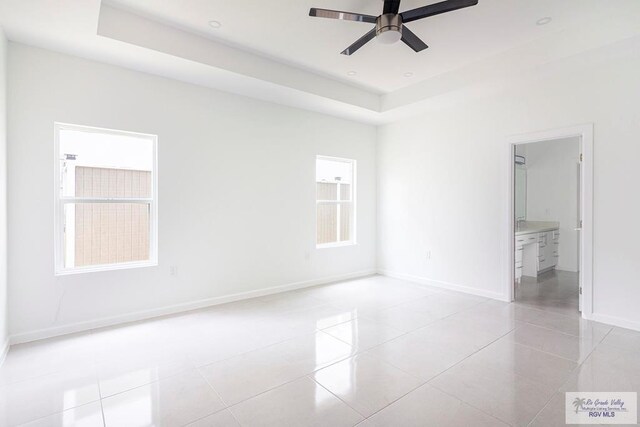 tiled spare room featuring ceiling fan and a tray ceiling