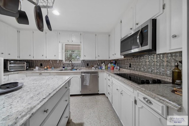 kitchen featuring decorative backsplash, light stone counters, stainless steel appliances, sink, and white cabinets