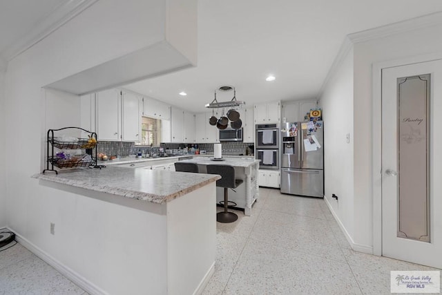 kitchen featuring kitchen peninsula, a breakfast bar, ornamental molding, and appliances with stainless steel finishes