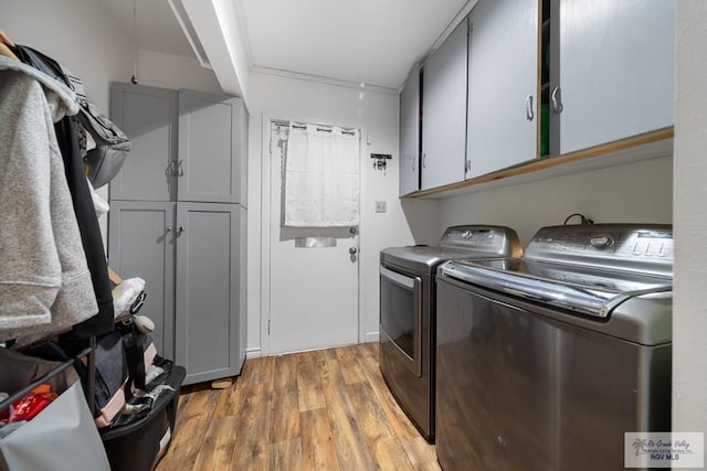 clothes washing area with washer and clothes dryer, cabinets, and wood-type flooring