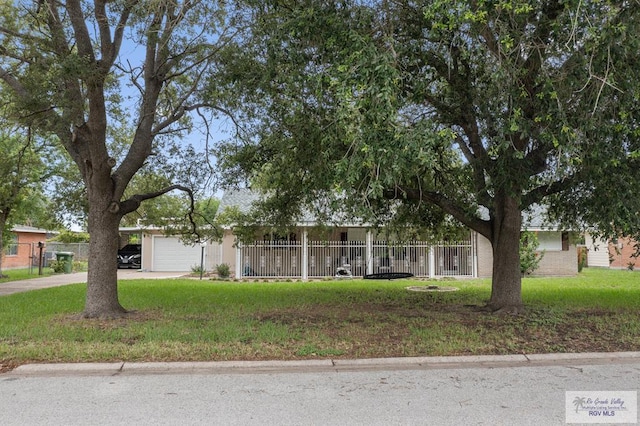 view of property hidden behind natural elements with a front yard and a garage