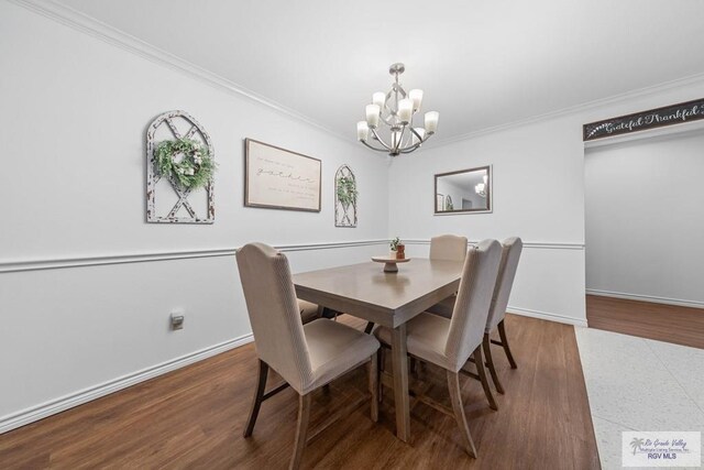 dining room featuring dark hardwood / wood-style floors, crown molding, and an inviting chandelier