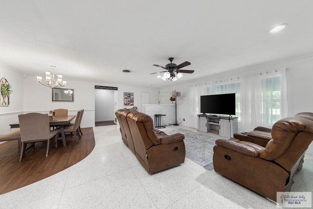 living room with ceiling fan with notable chandelier and ornamental molding