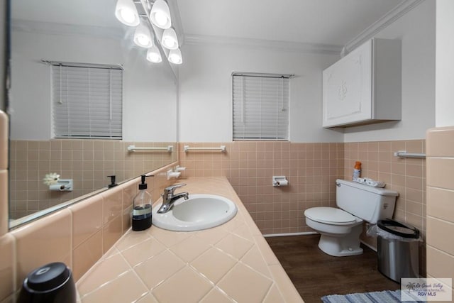 bathroom with vanity, hardwood / wood-style flooring, toilet, ornamental molding, and tile walls