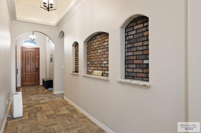 hallway with ornamental molding and an inviting chandelier