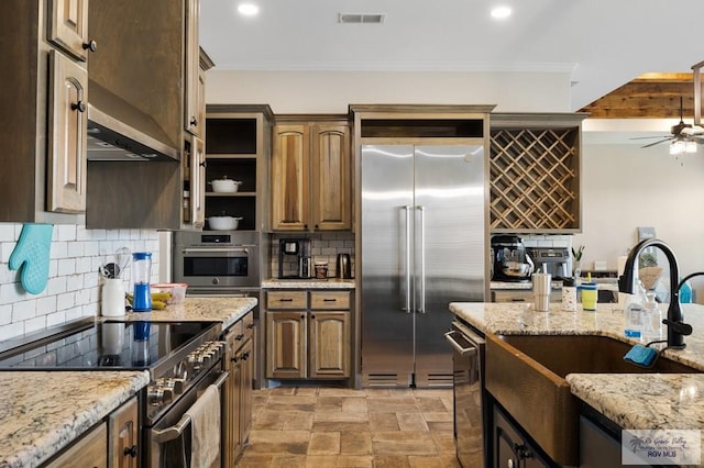 kitchen with decorative backsplash, ceiling fan, high end appliances, and light stone countertops