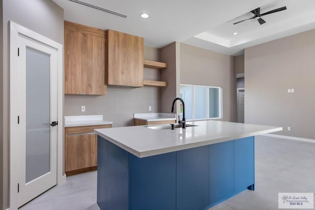 kitchen featuring a kitchen island with sink, sink, light tile patterned floors, and ceiling fan