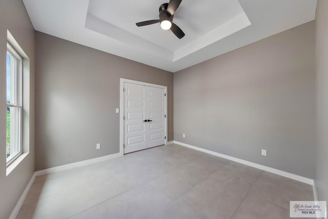 unfurnished bedroom with a raised ceiling and ceiling fan