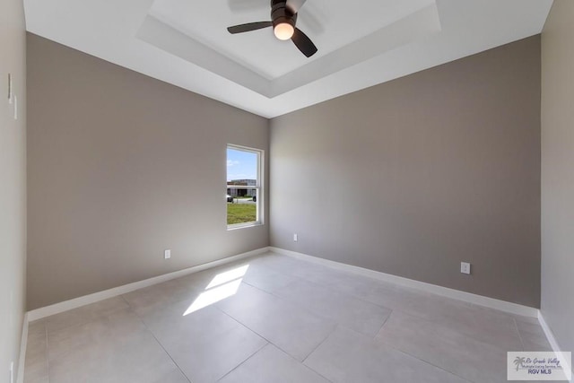 spare room with a raised ceiling, light tile patterned flooring, and ceiling fan