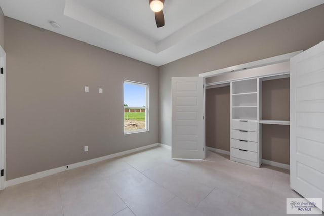 unfurnished bedroom with a tray ceiling, ceiling fan, and light tile patterned flooring