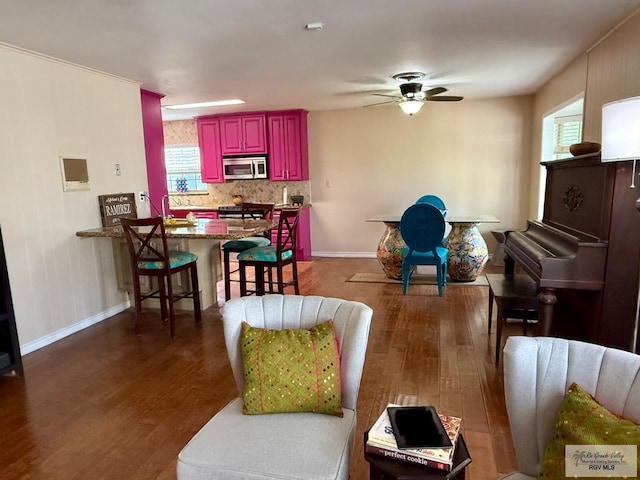 interior space with a breakfast bar, ceiling fan, stainless steel appliances, dark hardwood / wood-style flooring, and decorative backsplash