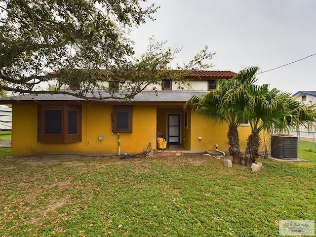 rear view of house with a lawn and central AC