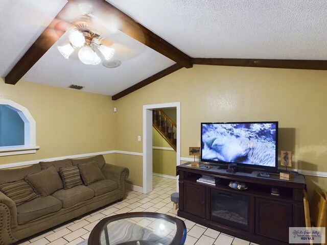 living room with vaulted ceiling with beams, ceiling fan, light tile patterned floors, and a textured ceiling