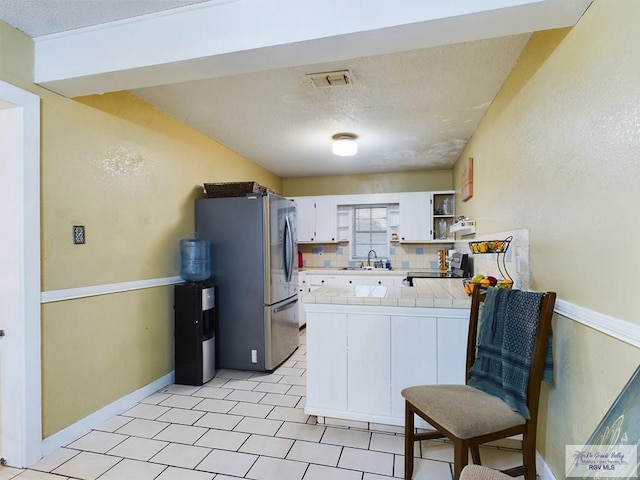 kitchen with backsplash, white cabinets, sink, appliances with stainless steel finishes, and tile counters