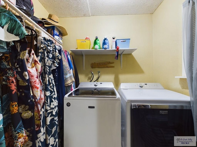 clothes washing area with washer and dryer and a textured ceiling