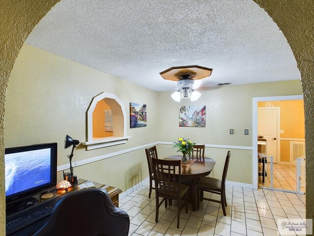 dining room featuring light tile patterned floors, a textured ceiling, and ceiling fan