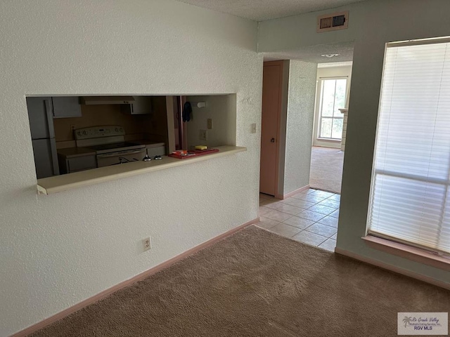 2901 Central Blvd, Brownsville, TX 78520 - kitchen with white electric range oven, exhaust hood, light colored carpet, baseboards, and light tile patterned floors