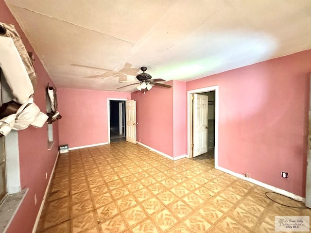 spare room with ceiling fan, light floors, and baseboards