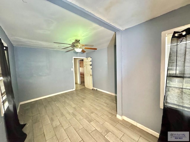 empty room featuring ceiling fan, baseboards, and wood finished floors