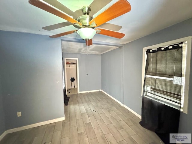 empty room featuring wood finished floors, a ceiling fan, and baseboards