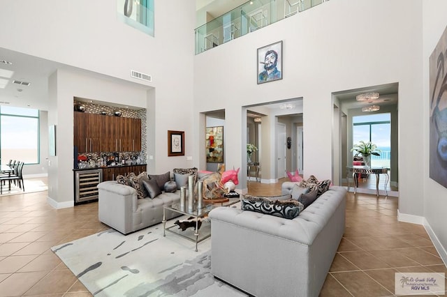 tiled living room featuring a towering ceiling and beverage cooler