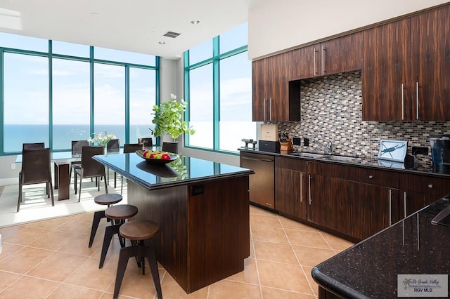 kitchen with dishwasher, a water view, sink, tasteful backsplash, and a kitchen island