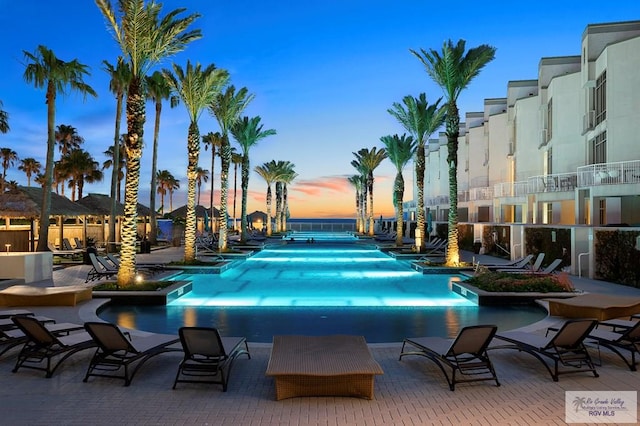 pool at dusk featuring a patio area