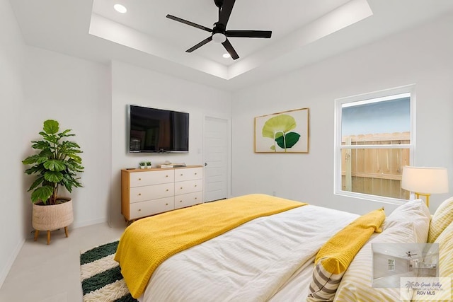 bedroom with ceiling fan and a tray ceiling