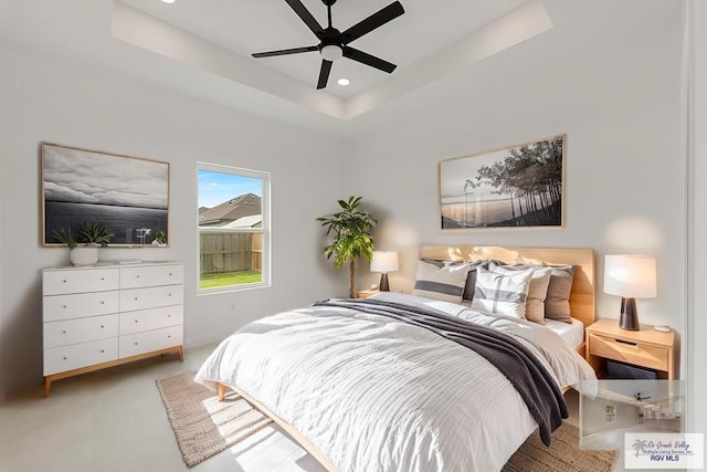 bedroom with ceiling fan, a raised ceiling, and light colored carpet