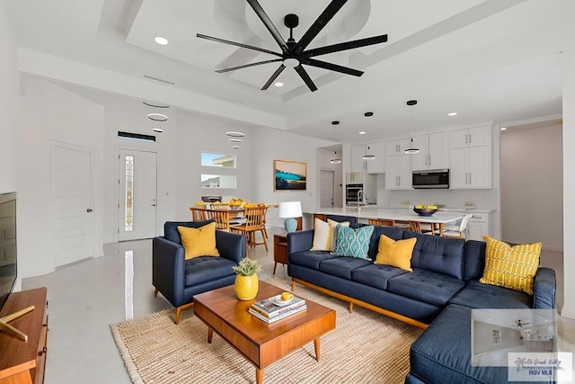 living room with a tray ceiling and ceiling fan