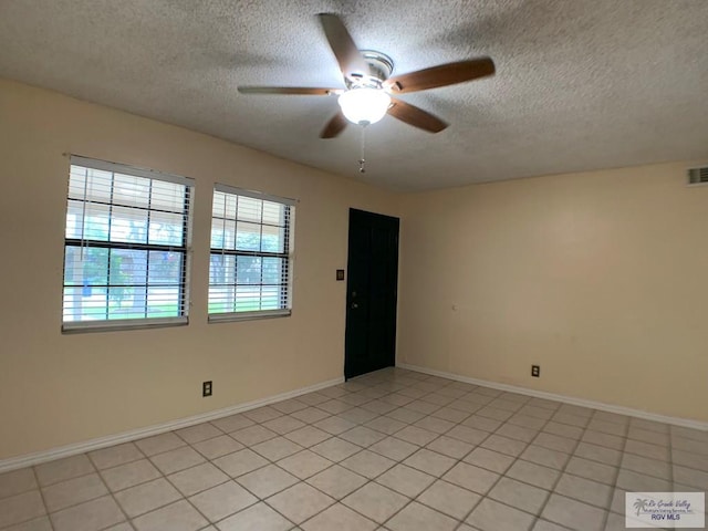 empty room featuring light tile patterned floors, visible vents, a ceiling fan, a textured ceiling, and baseboards