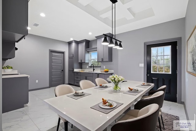 dining area with coffered ceiling, sink, beam ceiling, and a healthy amount of sunlight