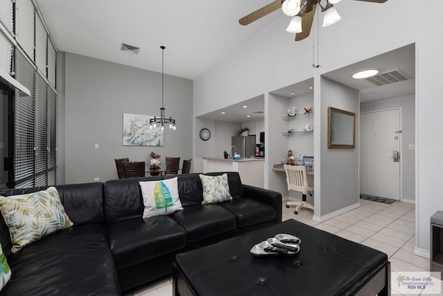 living room featuring ceiling fan with notable chandelier, light tile patterned floors, and a high ceiling