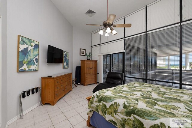 bedroom with ceiling fan, light tile patterned floors, and a high ceiling